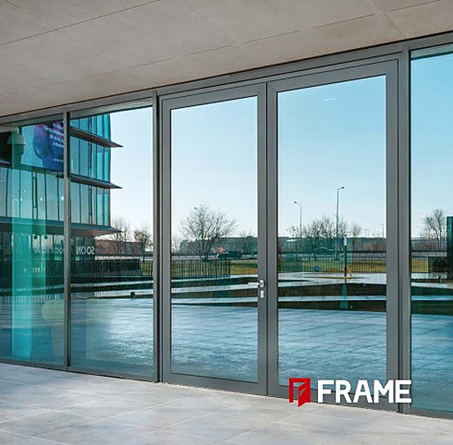 FRAME aluminum double swing doors with grey frames on a commercial building facade
