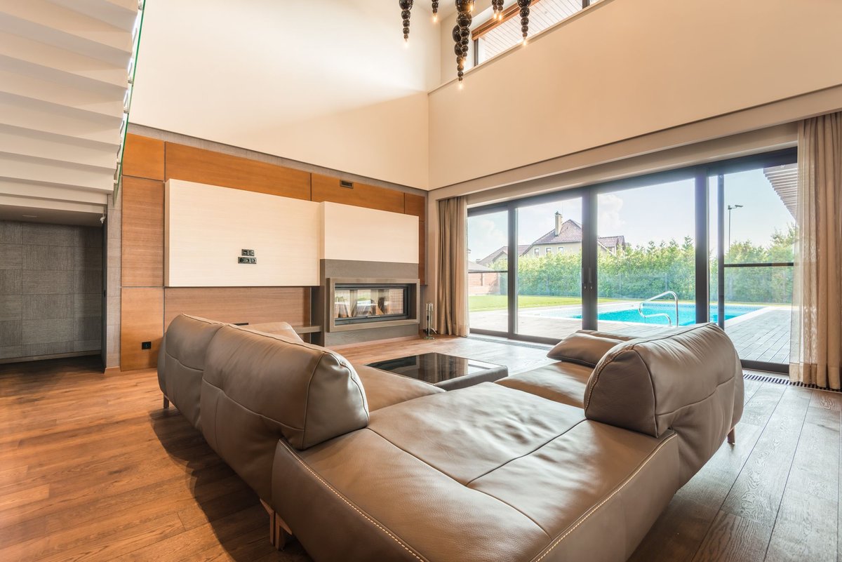 Living room with large dark-framed sliding glass doors opening onto a pool deck